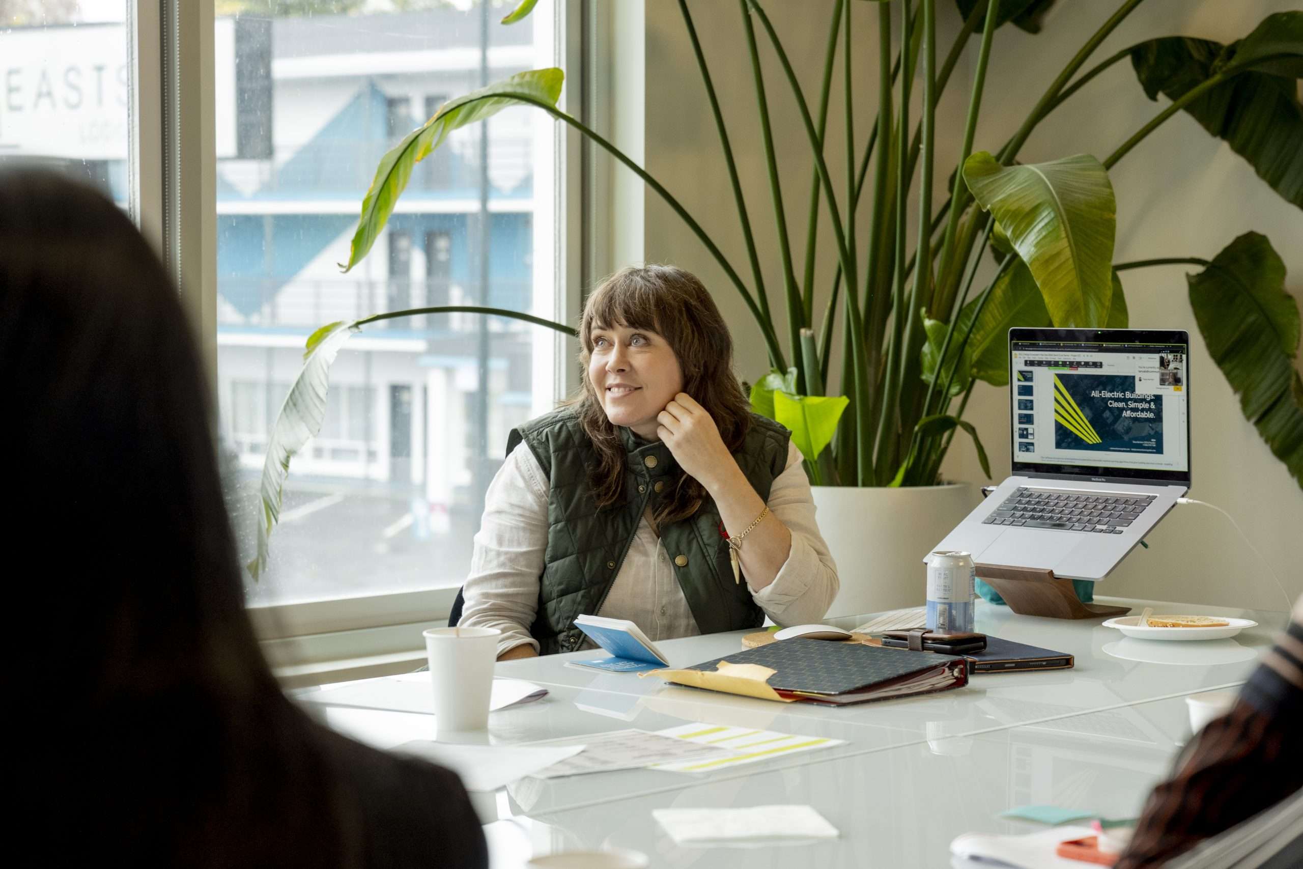 Tanya at a table listening to coworkers in an office.